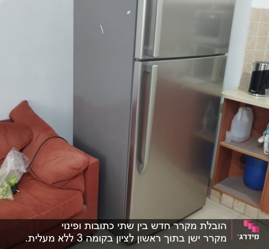 מקרר כסוף ליד ספה אדומה במטבח